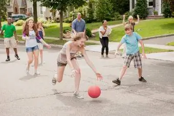 Niños jugando kickball en un barrio suburbano