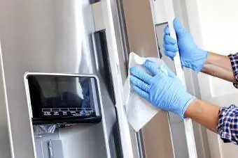Uomo che pulisce il frigorifero con una salvietta disinfettante
