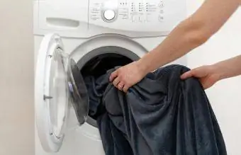Battaniyeyi çamaşır makinesine koyan kadın