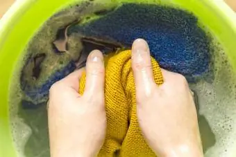 बेसिन में रंगीन कपड़े धोती महिला के हाथ