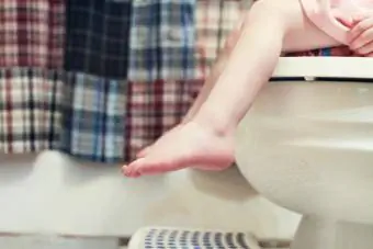 Tuvalet lazımlığının üzerinde oturan kız bacakları