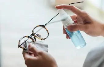 nainen puhdistaa silmälasien pintaa