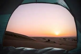 Malowniczy widok na wydmy widziane przez namiot na piasku na tle czystego nieba podczas