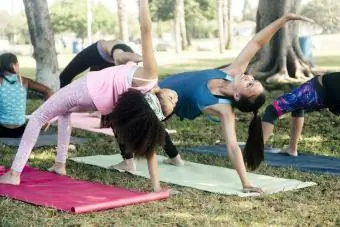 Skolnieces, kas praktizē jogas pozu skolas spēles laukumā