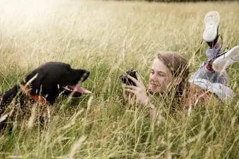 किशोरी पार्क में अपने लैब्राडोर रिट्रीवर कुत्ते की तस्वीरें लेती है