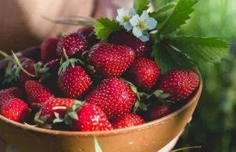 Värskeid maasikaid korjav inimene