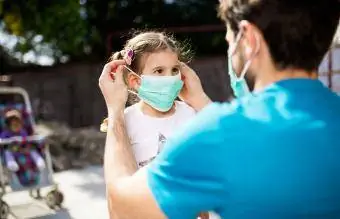 vader brengt masker aan op zijn dochter