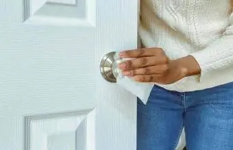 زن دستگیره در را با استفاده از دستمال ضد عفونی کننده تمیز می کند