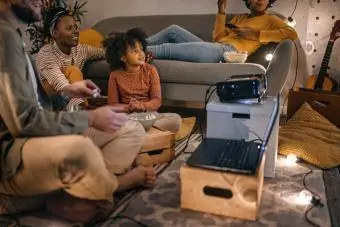 Porodica sjedi zajedno i gleda film na platnu projektora