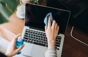 dizüstü bilgisayarın yüzeyini temizleyen kadın