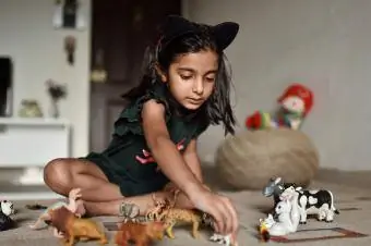dekle postavlja živalske igrače v vrsto