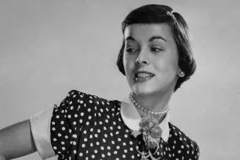 1950. gadu sieviete ar ziedu saktas un pērļu kaklarotas aksesuāriem