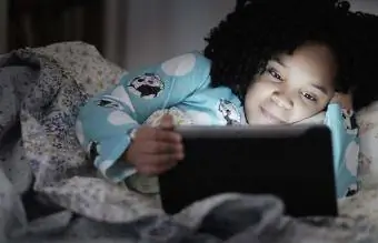 tyttö käyttää digitaalista tablettia sängyssä