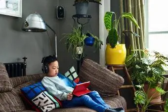 Мальчик в наушниках смотрит фильм на планшете