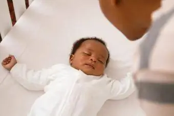 Afrikansk baby sover i barneseng
