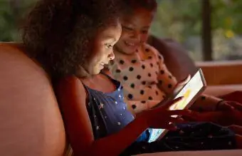 Dwie młode dziewczyny bawiące się na tablecie cyfrowym