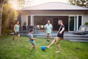 Famiglia multigenerazionale che gioca a calcio in cortile