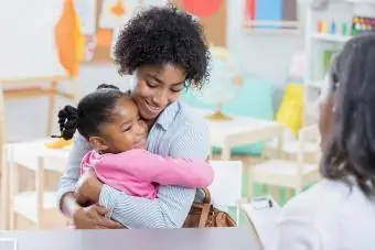 Klein meisje knuffelt moeder tijdens interview met kinderopvang