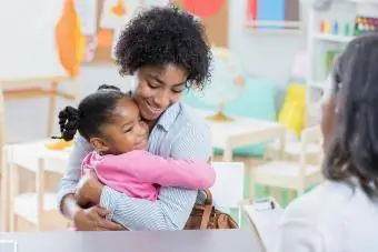 Menina abraça mãe durante entrevista na creche