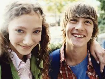 Teenager-Mädchen steht lächelnd mit dem Arm um ihre Freundin