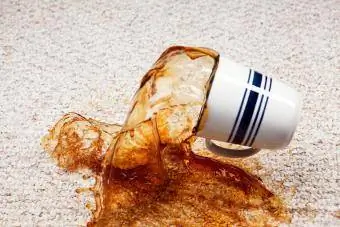 Kaffee läuft aus der Tasse auf den Teppich