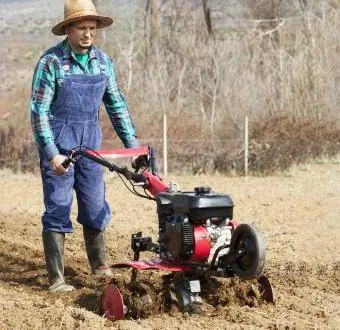 L'homme cultive la terre avec le cultivateur