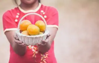 Menina segurando uma cesta de laranja