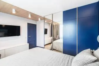 Pemandangan ke tempat tidur king size, TV, dan pintu masuk di kamar tidur yang terang dan nyaman