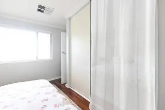 Prázdná manželská postel se odráží od zrcadla vestavěné skříně