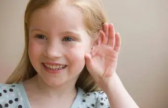 Niña ahuecando la oreja para oír mejor