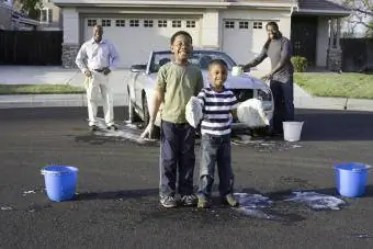 Aileleri arabayı yıkarken erkekler süngerlerle oynuyor