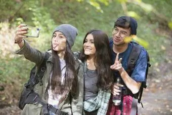 Twee meisjes en een jongen wandelen in het bos en stoppen om een selfie te maken