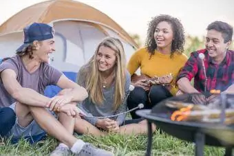 Grup d'amics asseguts al voltant de la foguera i acampant