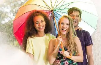 Χαρούμενοι φίλοι κάτω από την ομπρέλα