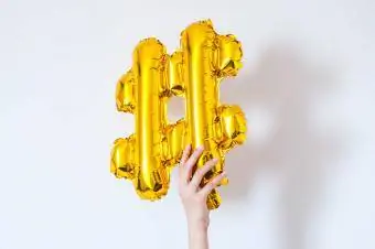 Tangan memegang hashtag balon emas