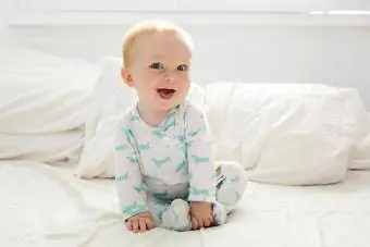 Мальчик (6-11 месяцев) лежит на кровати.