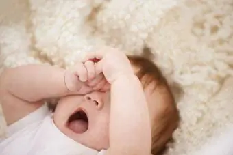 utrujen dojenček zeha in si drgne oči