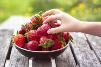 लड़की का हाथ स्ट्रॉबेरी ले रहा है