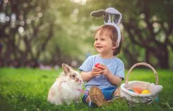 Niño jugando con conejito y huevos de Pascua