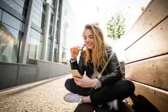 tiener wat sjokolade op telefoon eet buite in straat