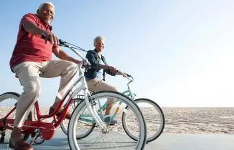 समुद्र तट के किनारे साइकिल चलाते युगल