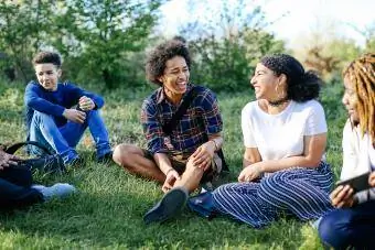 Teenager sitzen lachend im Gras