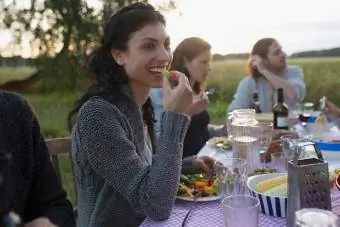 Hymyilevä nainen syömässä ystävien kanssa