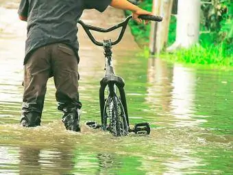 Mies polkupyörän kanssa seisomassa vedessä