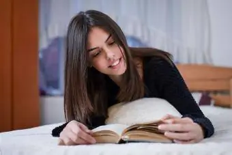 Genç kız yatakta kitap okuyor