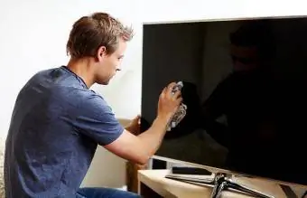Homme nettoyant l’écran de sa télévision intelligente
