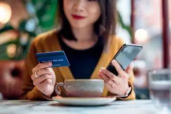 Donna che acquista online sullo Smart Phone in un caffè