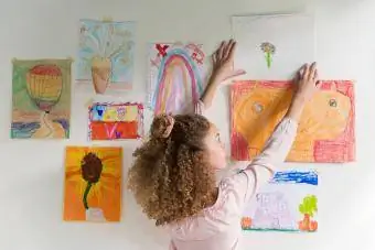 Mädchen hängt Kunstwerke an die Wand
