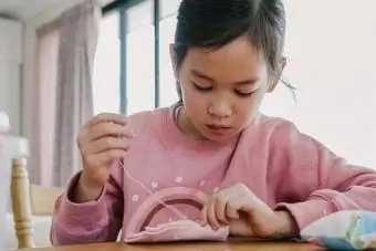 niña cosiendo en casa