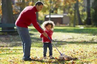 baba ve kız sonbahar sonbahar yapraklarını tırmıklıyor